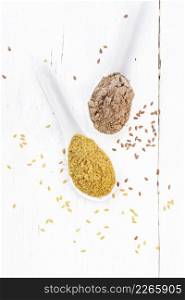 Flaxseed bran and flour in two spoons, seeds on a wooden board background from above