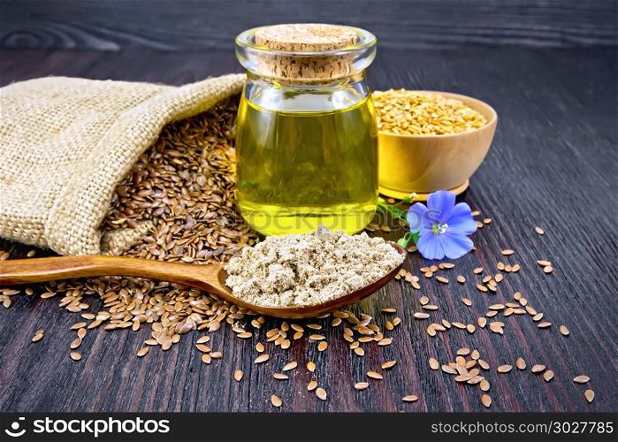 Flaxseed flour in a spoon, oil in a glass jar, blue flax flower, brown seeds in a bag and white linen seeds in a bowl on a wooden board background. Flour linen in spoon with oil and seeds on board