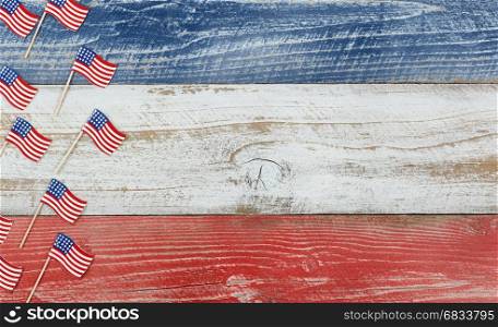 Flay lay view of USA mini flags on rustic wooden boards painted in red, white and blues colors.