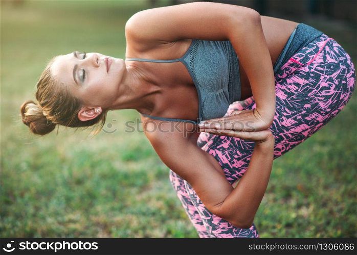 Flexible woman meditating, yoga training on the grass in summer park. Morning yogi meditation. Flexible woman meditating, yoga training