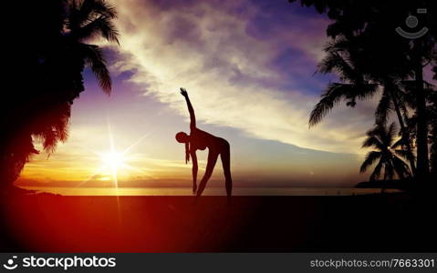 Flexible woman training on a tropical beach