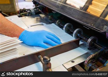 Flexo printing machine in a print factory. Flexo printing machine in a print factory operator hand detail