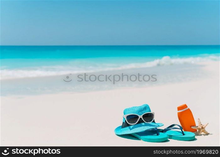 Flip flop, suncream bottles, goggles, starfish and sunglasses on white sand beach background ocean. Suncream bottles, goggles, starfish and sunglasses on white sand beach background ocean
