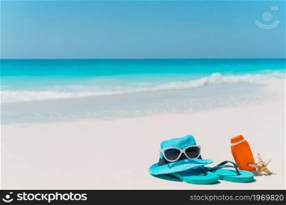 Flip flop, suncream bottles, goggles, starfish and sunglasses on white sand beach background ocean. Suncream bottles, goggles, starfish and sunglasses on white sand beach background ocean