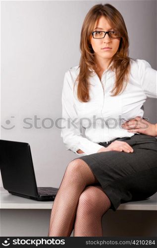flirting sexy business woman is sitting on table in the office