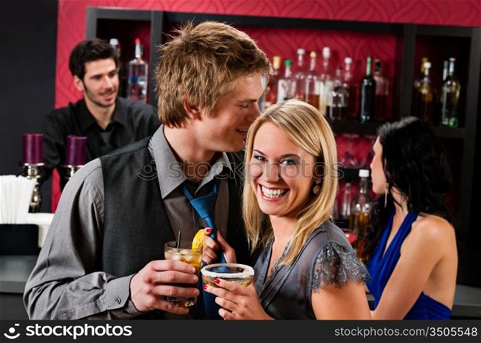 Flirting young happy friends enjoy drinks at cocktail bar