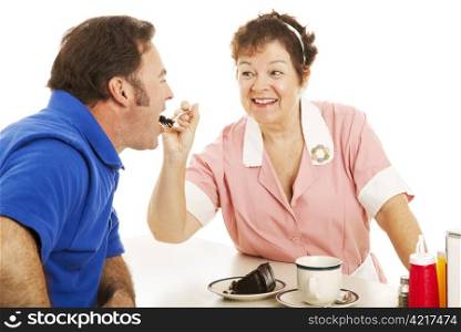 Flirty waitress feeding chocolate cake to her customer. White background.