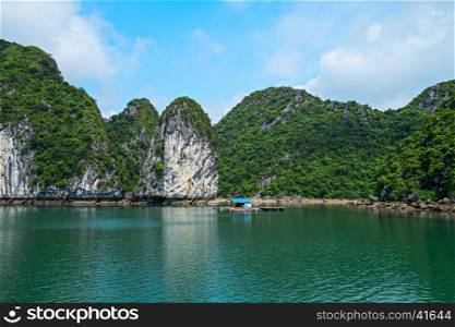 Floating house and rock islands in Halong Bay, Vietnam, Southeast Asia. UNESCO World Heritage Site. Scenic landscape mountain sea at Ha Long Bay. Most popular landmark, tourist destination of Vietnam.. Floating house, rock islands, Halong Bay, Vietnam