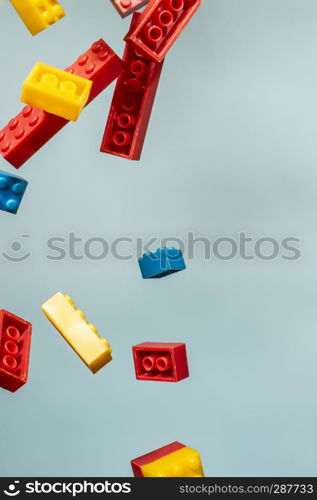 Floating Plastic geometric cubes in the air. Construction toys on geometric shapes falling down in motion. Blue pastel background. Children's toys. Circle geometric shapes on plastic bricks.