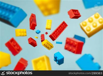Floating Plastic geometric cubes in the air. Construction toys on geometric shapes falling down in motion. Blue pastel background. Children's toys. Circle geometric shapes on plastic bricks.