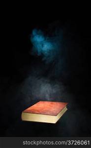 Floating unopened book and smoke, dark background