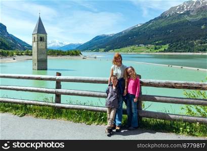 Flooded (in 1950) bell tower in Reschensee and family (Italy, church building in 14th-century)