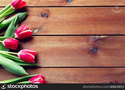 flora, gardening and plant concept - close up of red tulip flowers on wooden table with copy space