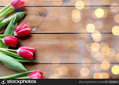 flora, gardening and plant concept - close up of red tulip flowers on wooden table with copy space