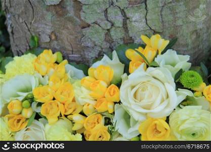 Floral arrangement in yellow and white near a tree