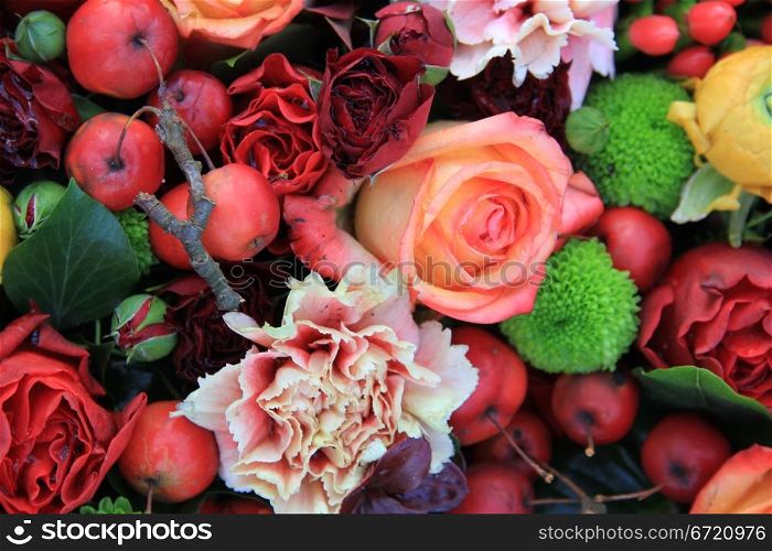 Floral arrangement with roses, berries and leaves in different shades of red and orange