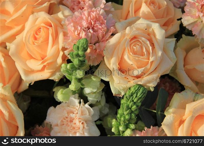 Floral arrangement with soft orange roses and carnations