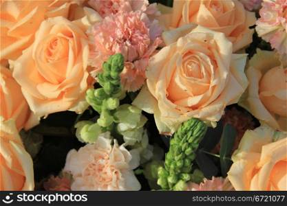 Floral arrangement with soft orange roses and carnations