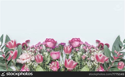 Floral border made from various pink flowers and green leaves on white background. Roses, tulips and daisies. Top view with copy space.
