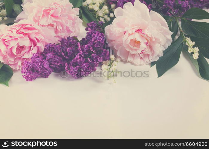 Floral borders of fresh flowers - lilac, peonies and lilly of the walley flowers on white background, retro toned. Floral borders