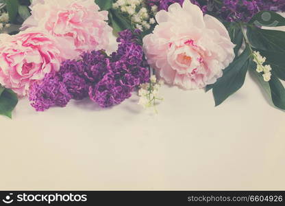 Floral borders of fresh flowers - lilac, peonies and lilly of the walley flowers on white background, retro toned. Floral borders