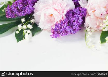 Floral borders of fresh flowers - lilac, peonies and lilly of the walley flowers and leaves on white background. Floral borders