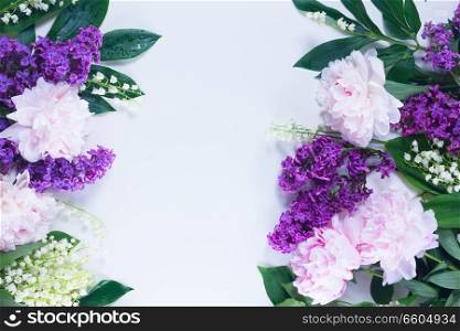 Floral borders of fresh flowers - lilac, peonies and lilly of the walley fresh flowers on white background with copy space. Floral borders on white