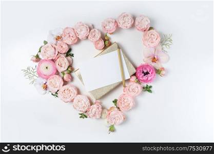 Floral composition. Heart frame made of pink rose and ranunculus flowers on white background. Flat lay, top view, copy space on card. Flowers flat lay composition