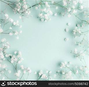 Floral composition with light, airy masses of small white flowers on turquoise blue background, top view, frame. Gypsophila Baby?s-breath flowers