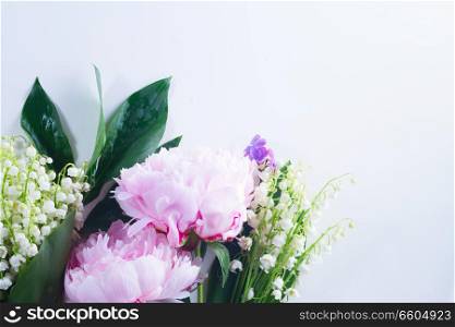 Floral flat lay scene of fresh flowers - lilac, peonies and lilly of the walley flowers on white background. lilac, pink peonies and lilly of the walley