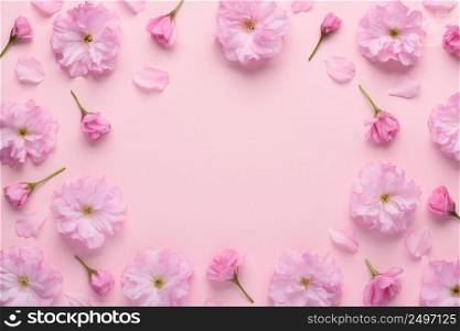 Floral pattern of blooming sakura flowers with buds and petals on pink pastel background. Flower pattern frame composition with copy space.