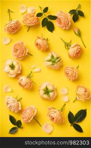 Floral pattern with pink roses and leaves on yellow background, flat lay