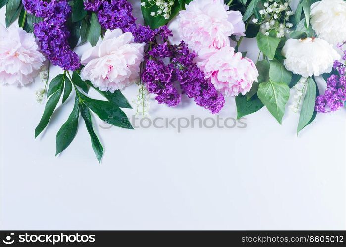 Floral spring border - lilac, peonies and lilly of the walley flowers on white background, flat lay scene with copy space. Floral borders on white
