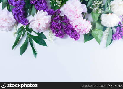 Floral spring border - lilac, peonies and lilly of the walley flowers on white background, flat lay scene with copy space. Floral borders on white