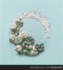 Floral Wreath made of white flowers, petals and blossom on pastel blue background. Spring and summer concept. Floral frame. Flat lay, top view. Invitation or card for wedding, birthday and other