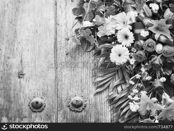 Floral wreath on weathered wooden door with copy space in stunning black and white