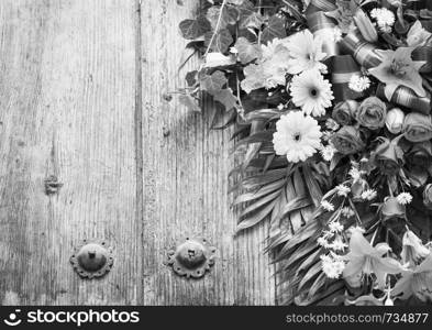 Floral wreath on weathered wooden door with copy space in stunning black and white