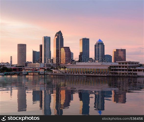 Florida skyline at Tampa with the Convention Center on the riverbank. Sun is just setting at dusk giving a fiery glow to the night sky.. City skyline of Tampa Florida at sunset