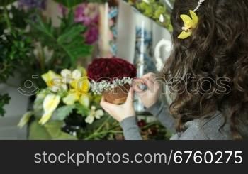 Florist arranging rose heart-shaped bouquet is surrounded by gypsophila in flower shop. Closeup