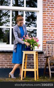 florist. girl makes a bouquet with pink tulips near with a traditional Dutch house. The Netherlands