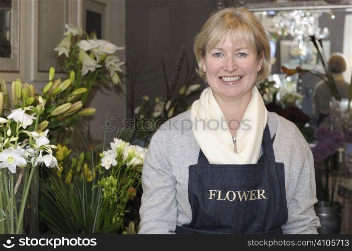 Florist in her shop surrounded by flowers smiling at camera