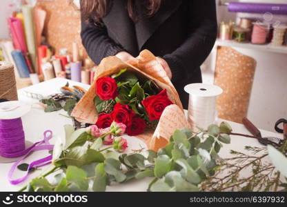 Florist making fashion bouquet of beautiful red roses. Florist making bouquet of red roses