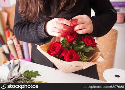 Florist making fashion bouquet of beautiful red roses. Florist making bouquet of red roses