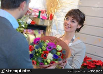 Florist passing colorful bouquet to customer