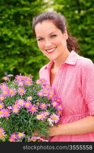 Florist smiling holding pink potted flower in garden shop greenhouse