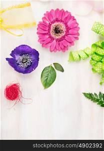 Floristic background with flowers and accessories on white wooden background, top view, place for text