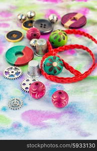 Floss and trinkets for needlework. spool of thread with beads and accessories for needlework on bright background