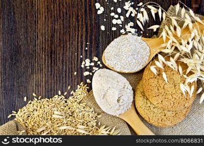 Flour and bran oaten in a spoons, stalks of oats, grits and biscuits on a background sacking on a wooden board