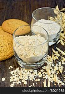 Flour and bran small oat in a two glassful, oatmeal and ears, cookies on a background of wooden boards
