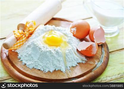 flour and raw eggs on the wooden board